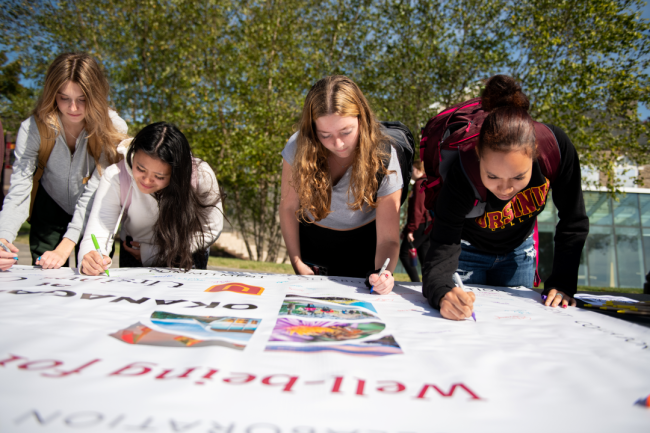 Four Ursinus College students sign a poster